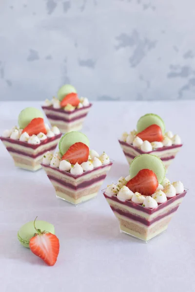 Sobremesa em xícaras com morangos frescos e macaroons em uma mesa branca — Fotografia de Stock