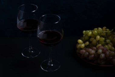 kırmızı şarap ve üzüm koyu arka plan üzerinde