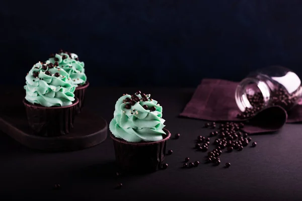 Cupcakes e polvilhas em um fundo escuro — Fotografia de Stock