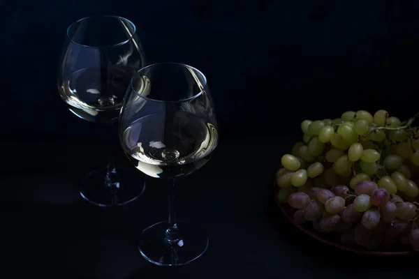 Белое вино и виноград на темном фоне — стоковое фото