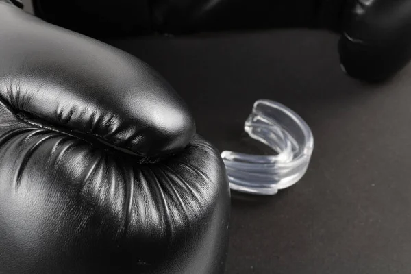 Boxing gloves and a mouth guard on a black background. product image