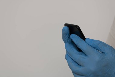 Ellerinde cep telefonu tutan nitril eldivenlerle korunan eller
