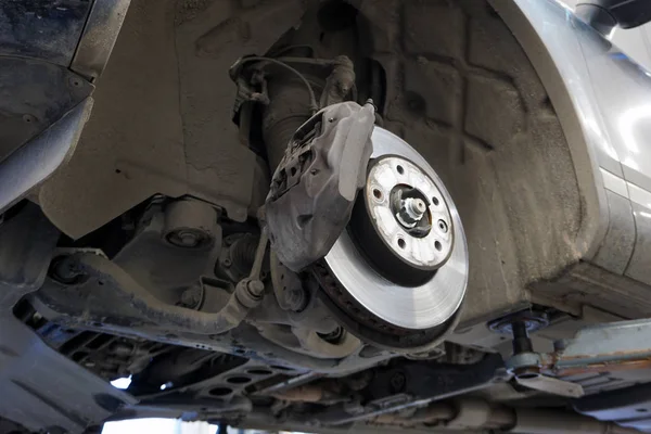 Modern bir arabanın ön fren mekanizmasının elementleri ve tasarımı, fren kalibreli, fren diski. Araba kaldırıldığında, aşağıdan arabanın görüntüsü. Hizmet merkezlerindeki fren mekanizmalarının zamanında servisi.