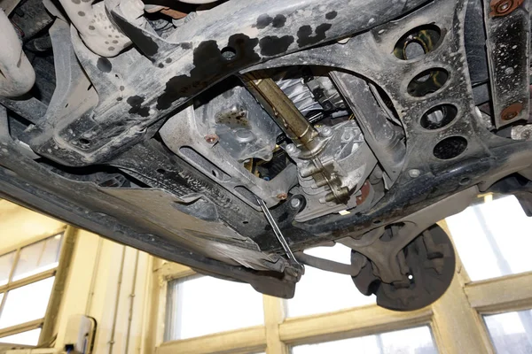 Motor yağı sızıntısı izleri. Araba asansörle kaldırılıyor, krankcase koruması kaldırılıyor, yağ sızıntısı görülüyor. Benzin istasyonunda modern bir arabanın teşhisi ve tamiri.