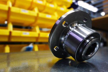 Yeni yüksek kalite yedek parça kavramı. Depo rafının bulanık arka planına sahip yeni orijinal tekerlek merkezi. Kalite, dayanıklılık ve güvenilirlik garantisi olarak yeni yedek parçalar. 