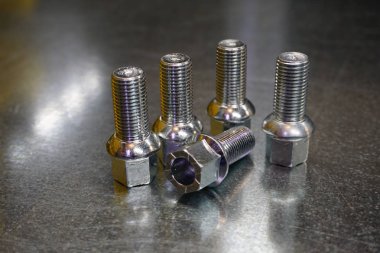 Çelik arka planda tekerlek cıvataları. Yeni yüksek kalite yedek parça kavramı. Kalite, dayanıklılık ve güvenilirlik garantisi olarak yeni yedek parçalar.  