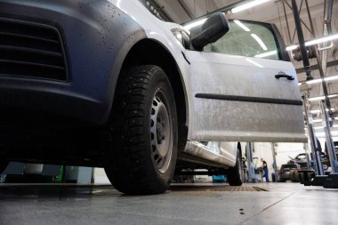 Beyaz araba serviste, aşağıdan görünüyor, arabanın ön tarafına odaklanıyor, arka plandaki servis bulanık..                  