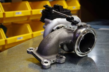 Çelik zemin üzerinde modern turbo şarj aleti. Turbo şarj elementi, egzoz gazlarını kullanarak motor gücünü önemli ölçüde artırmanızı sağlar. Araba tamiri için orijinal yüksek kaliteli yedek parça..        