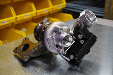 Çelik zemin üzerinde modern turbo şarj aleti. Turbo şarj elementi, egzoz gazlarını kullanarak motor gücünü önemli ölçüde artırmanızı sağlar. Araba tamiri için orijinal yüksek kaliteli yedek parça..        