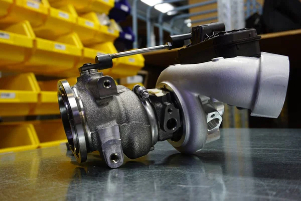 Çelik zemin üzerinde modern turbo şarj aleti. Turbo şarj elementi, egzoz gazlarını kullanarak motor gücünü önemli ölçüde artırmanızı sağlar. Araba tamiri için orijinal yüksek kaliteli yedek parça..        