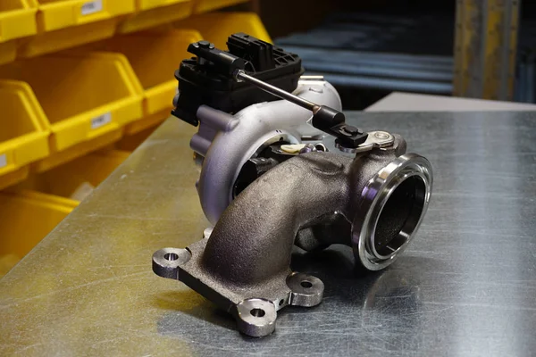 Çelik zemin üzerinde modern turbo şarj aleti. Turbo şarj elementi, egzoz gazlarını kullanarak motor gücünü önemli ölçüde artırmanızı sağlar. Araba tamiri için orijinal yüksek kaliteli yedek parça..        