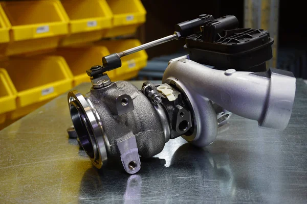 Çelik zemin üzerinde modern turbo şarj aleti. Turbo şarj elementi, egzoz gazlarını kullanarak motor gücünü önemli ölçüde artırmanızı sağlar. Araba tamiri için orijinal yüksek kaliteli yedek parça..        