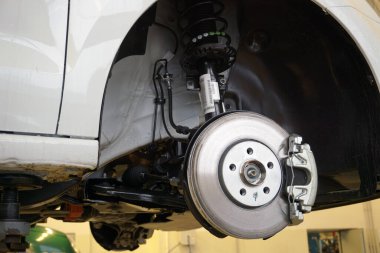 A modern luxury car at a service station is lifted on a lift for repair. Front brake disc, caliper. Quality after-sales service concept.  