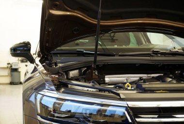 Modern luxury car at the service station. The hood is open on the car. The concept of modern quality car service. Quality spare parts concept.                    