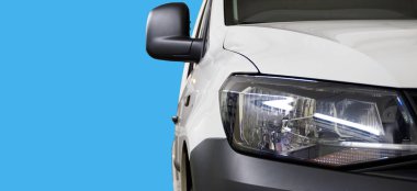 Concept. Service and repair of a modern car. Sale of high-quality spare parts for a modern car. In the photo the front of the car, close-up headlamp, plain background in blue.                                clipart
