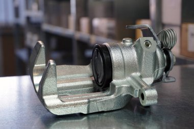 Çelik arka planda ön fren kalibreli yakın plan. Modern bir araba için orijinal yüksek kaliteli yedek parça. Araba için yedek parça depolama ve ticareti.  