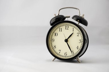 Beyaz arka planda klasik siyah yuvarlak alarm saati. Ofis konseptinde öğle yemeği zamanı. Herhangi bir evin ya da ofisin modern iç mekanına güzel bir katkı..