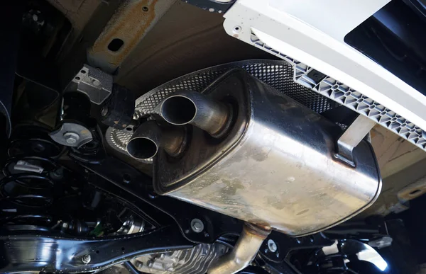 Modern bir arabanın arka egzozu. Araba asansörde, manzara aşağıdan. Yakın plan. Servis ve onarım, modern bir araba için yedek parça. Kavram.     