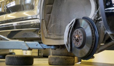 Asansörle yükseltilmiş modern lüks bir araba. Fren diski, fren ayarı modern bir arabaya monte edilmiş. Hizmet ve araba tamiri kavramı. 