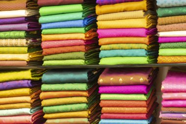 Hindistan 'ın tekstil galerisine istiflenmiş geleneksel renkli Hint kıyafetleri. Ağrılı ipek