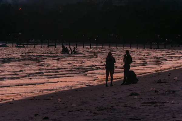 Deux randonneurs marchant sur la plage au coucher du soleil — Photo