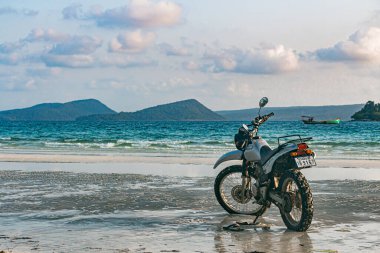 Kumsalda gümüş bir motosiklet duruyor.