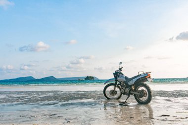 Kumsalda gümüş bir motosiklet duruyor.