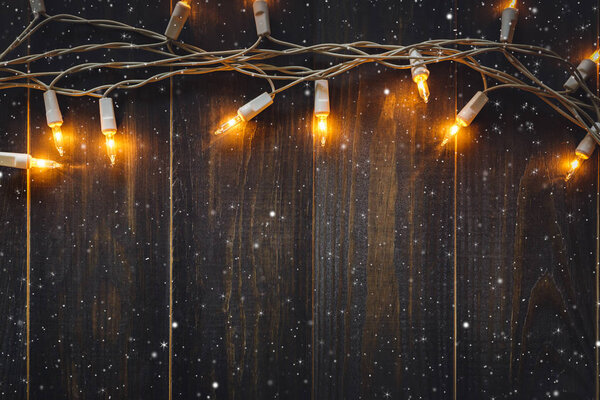 christmas background lights and snow with copy space on old wooden board background