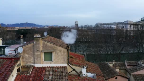 eine Drohne in Großaufnahme von den Dächern in Rom, mit rauchendem Schornstein im Vordergrund