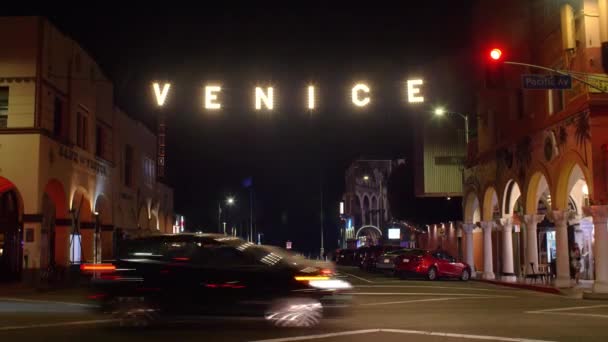 Sinal de VENICE brilhantemente iluminado pendurado sobreOcean Walk perto de Venice Beach, LA, à noite Filmagem De Stock