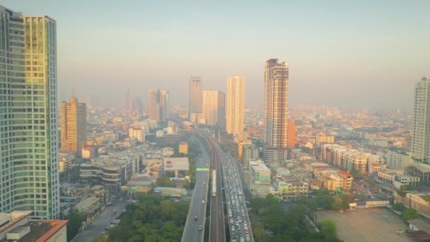 Drone shot panning up over a road and railway track in Bangkok at sunrise — Stock Video