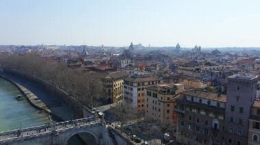 Önce Tiber Nehri 'nin üzerinden, sonra da Roma' nın çatılarının üzerinden uçuyor.