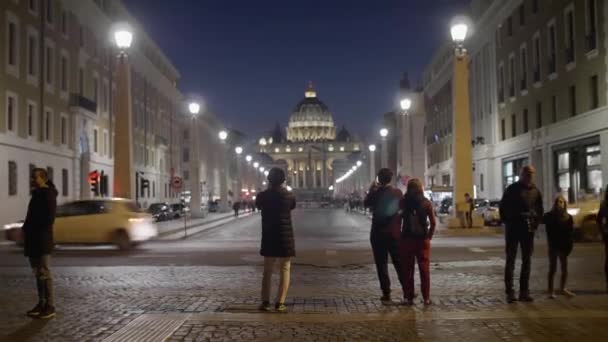 Люди фотографуються на вулиці Via della Concillazione, з базилікою St Peters на задньому плані, вночі — стокове відео