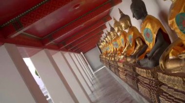 Wat Pho Tapınağı, Bangkok 'ta bulunan altın koltuklu Buda heykelleri boyunca dönen el kamerası görüntüleri.