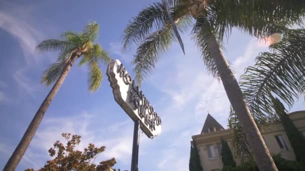 Знак для Голливудской башни в Лос-Анджелесе с пальмами на фоне голубого неба — стоковое видео