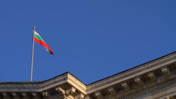 Imagens de câmera lenta da bandeira búlgara voando em um telhado contra um céu azul em Sófia, Bulgária — Vídeo de Stock