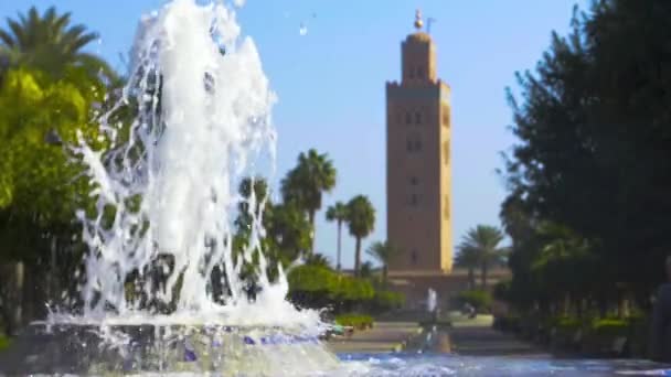 モロッコのマラケシュにあるクトゥビア・モスクのミナレットを明らかにする噴水の前を追跡する — ストック動画