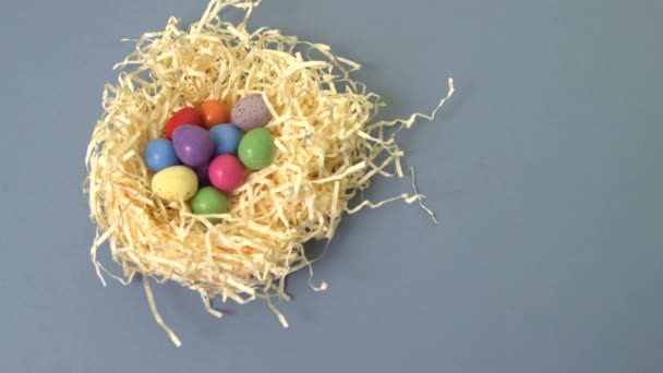 Mano colocando un colorido huevo de Pascua en un nido de paja — Vídeos de Stock