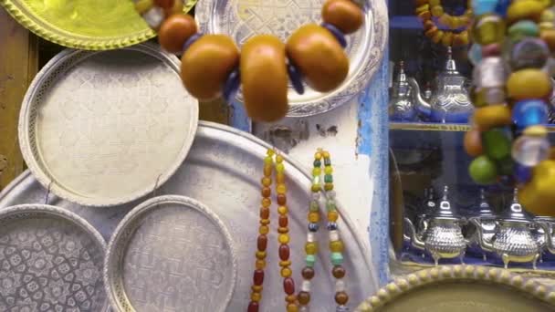 Handheld shot tracking past jewellery and beads on display outside a shop in Morocco — Stock Video