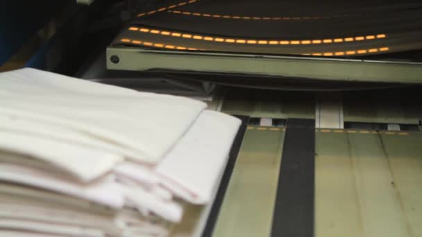 Maschine, die in einer industriellen Wäscherei stapelweise gefaltetes Bettzeug auf ein Förderband lädt — Stockvideo