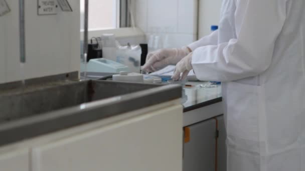 Ученый тестирует образец и записывает результаты в научной лаборатории — стоковое видео