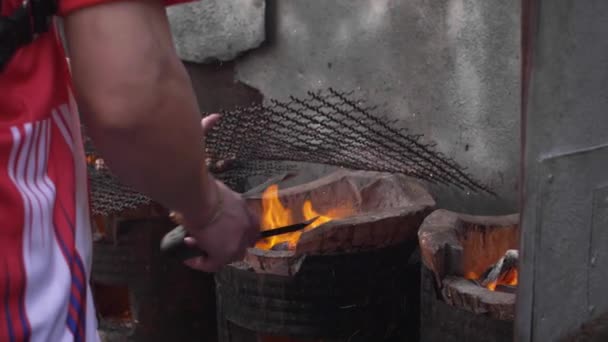 Vendeur de nourriture de rue ajustant les charbons sur un barbecue dans un étal à Chinatown, Bangkok — Video