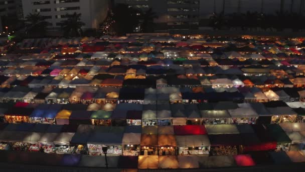 Drone estacionário disparado olhando para fora sobre o mercado de trem de Rachada em Bangkok à noite — Vídeo de Stock