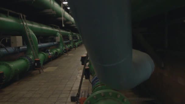 Tracking across a brightly lit industrial hallway with pipes and valves — Stock Video