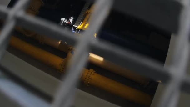 Verfolgung entlang großer Wasserrohre durch ein Metallgitter in einer Fabrik — Stockvideo