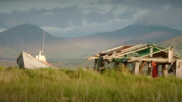 Barco y cabaña de pesca en pastizales bajo una montaña en Alaska — Vídeo de stock