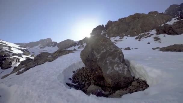 Ręczne ujęcia orbitujące wokół znacznika drogi na zaśnieżonej ścieżce górskiej w górach Atlas, Maroko — Wideo stockowe