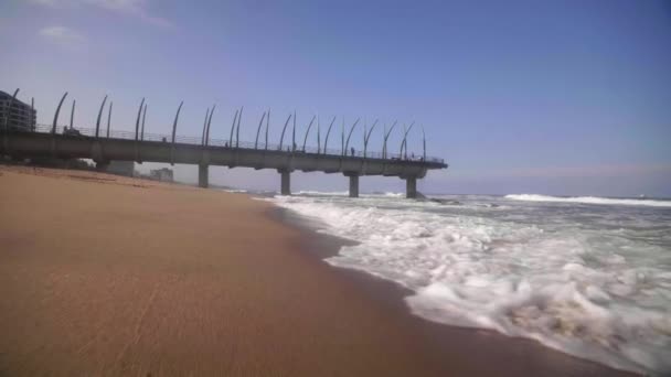 Slow motion shot of waves coming up onto Umhlanga Rocks Beach, with Whalebone Pier in the background — Stock Video