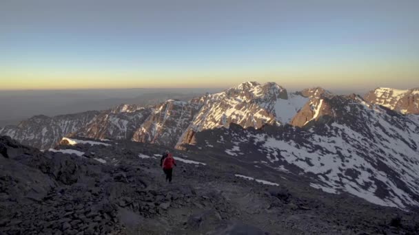 Dois caminhantes nas Montanhas Atlas, olhando sobre a cordilheira ao pôr do sol — Vídeo de Stock