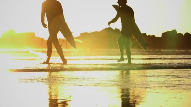 Slow motion pan of surfers entering the sea — Stock Video